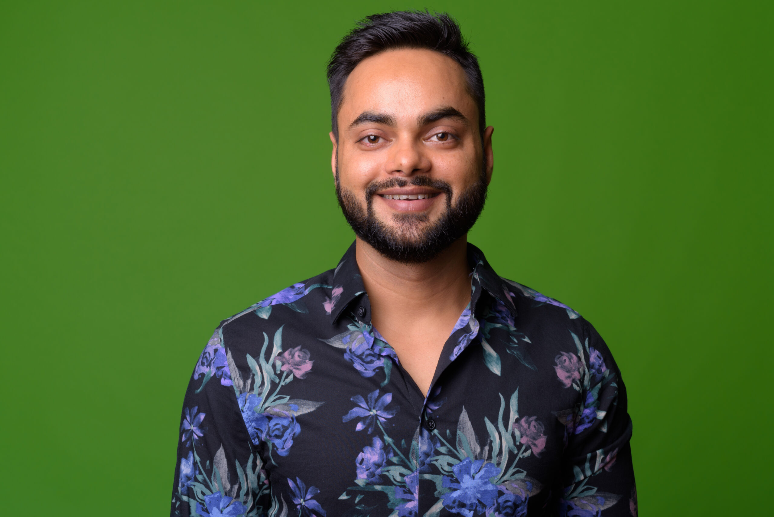 Studio shot of young bearded Indian man against chroma key with green background